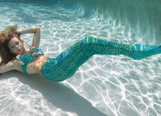 A model wearing different wardrobe above and below surface of water in a pool.